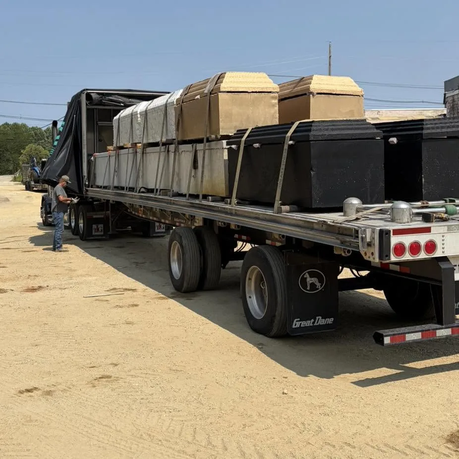 Flatbed trailer loaded with burial vaults and grave liners strapped down for shipment to Missouri